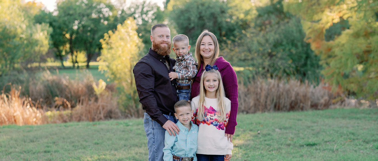 A smiling family of five standing in a field