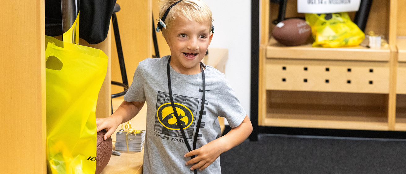 A young boy standing in a locker room and smiling