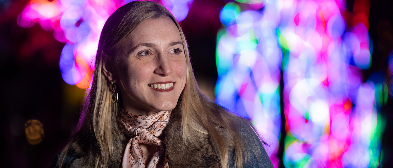 A woman smiling with many different colored lights behind her