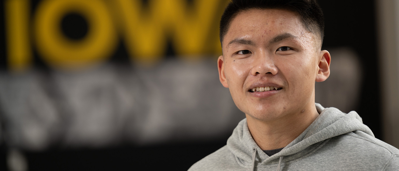 A man smiling with an IOWA poster behind him