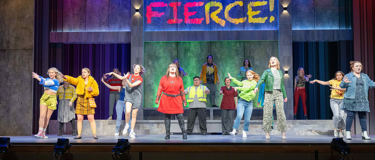 A group of performers on stage singing and dancing