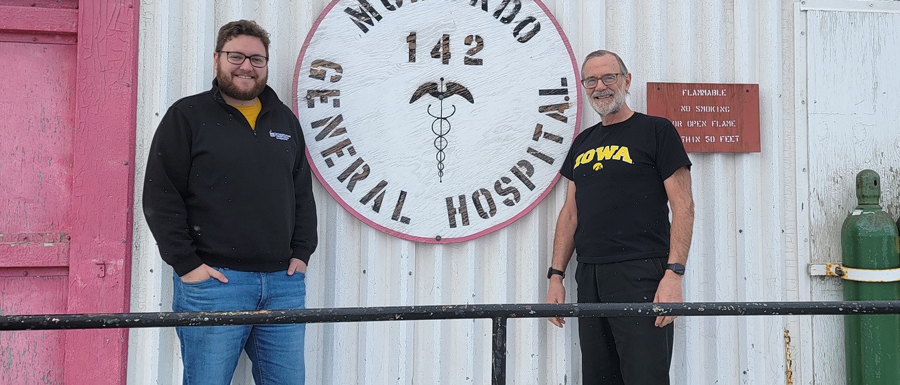 Two men standing outside of a hospital smiling
