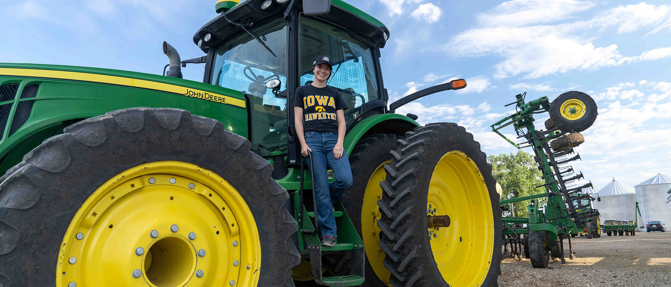 A woman standing on the ladder to a tractor