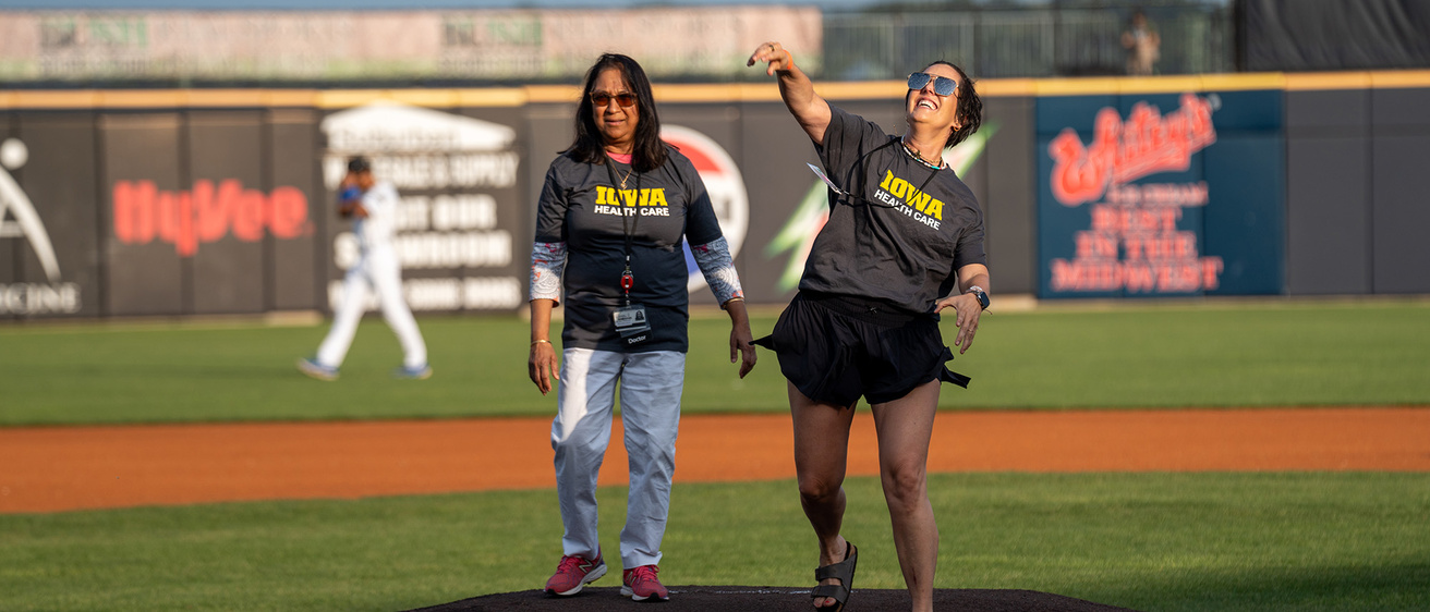 Two people standing on a pitcher's mound as one of them throws a ball