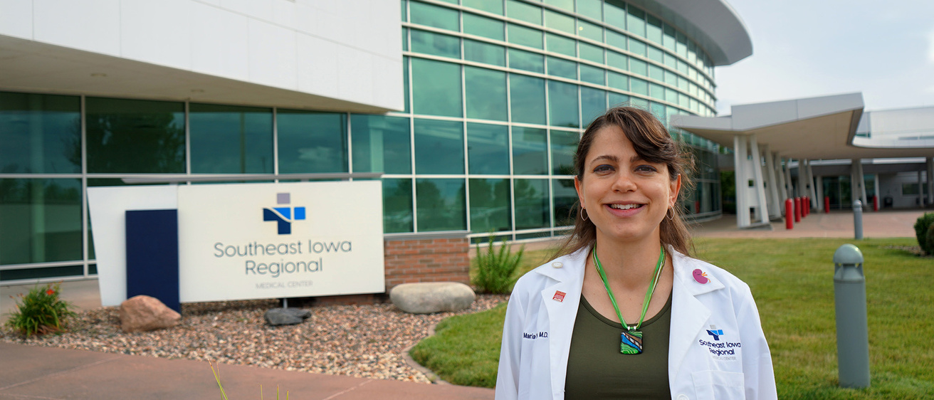 A doctor standing outside a hospital while smiling