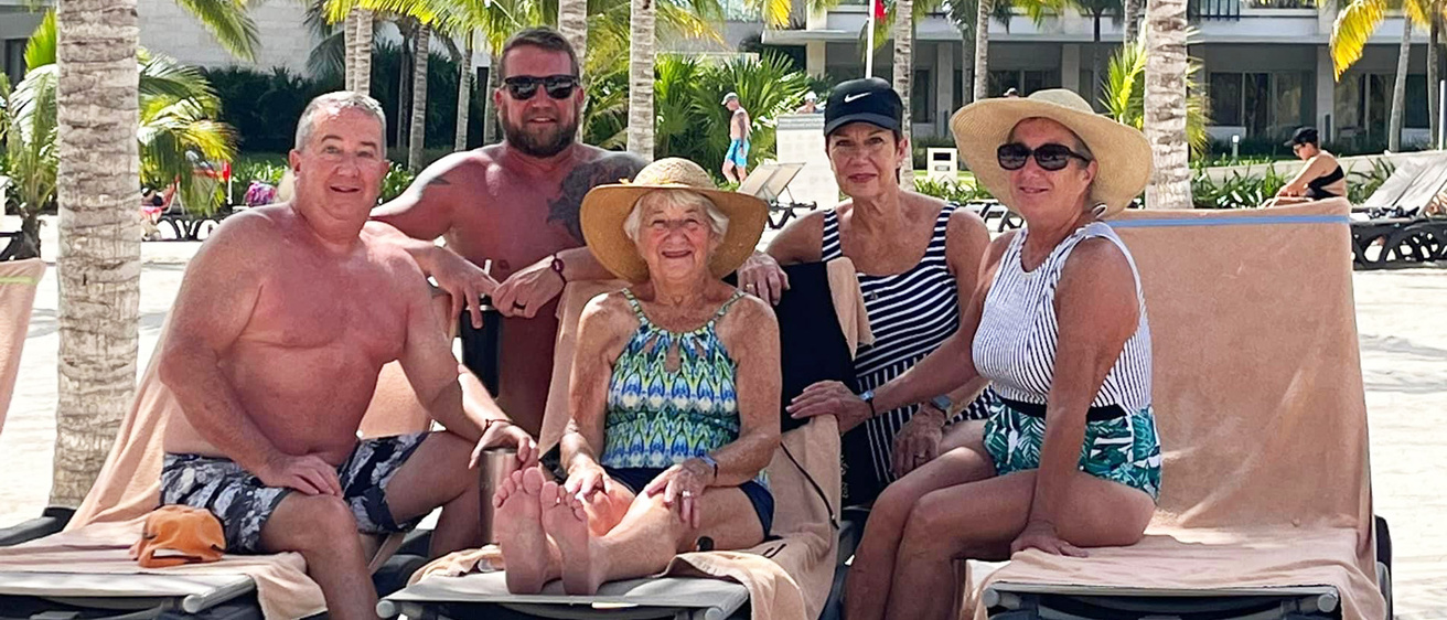 A group of people siting on the beach and smiling