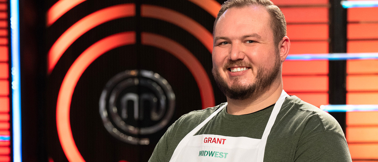 A photo of a man smiling dressed in an apron