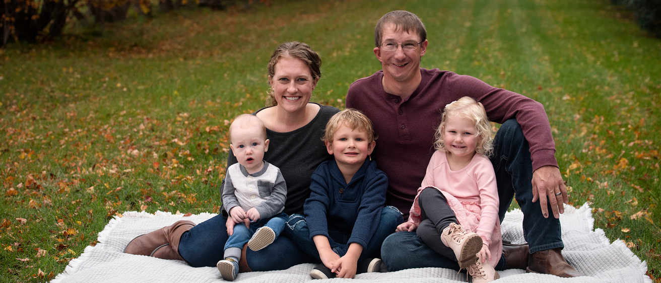 A family of five sitting outside on a blanket