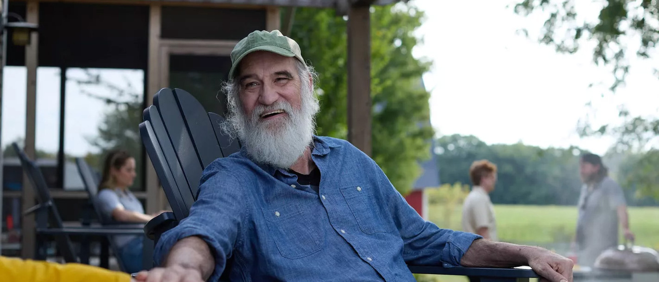 A man sitting in a chair smiling and holding someone's hand