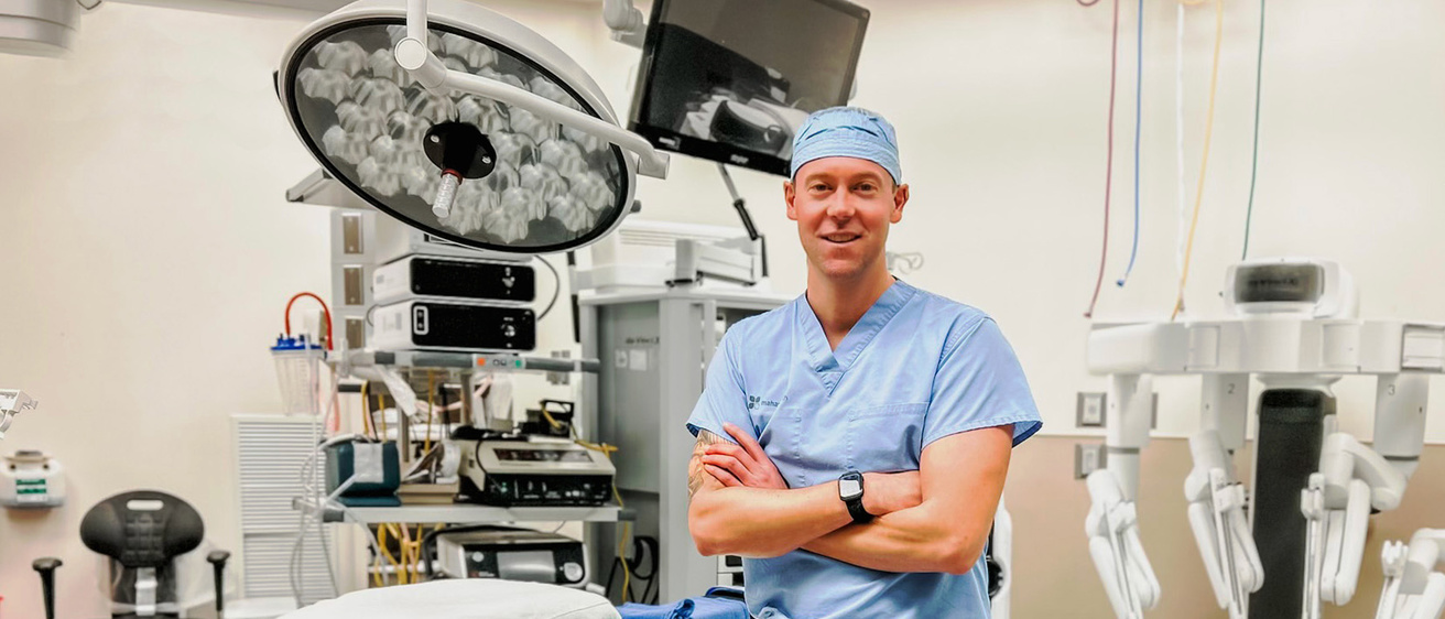 A doctor in scrubs leaning against a hospital bed