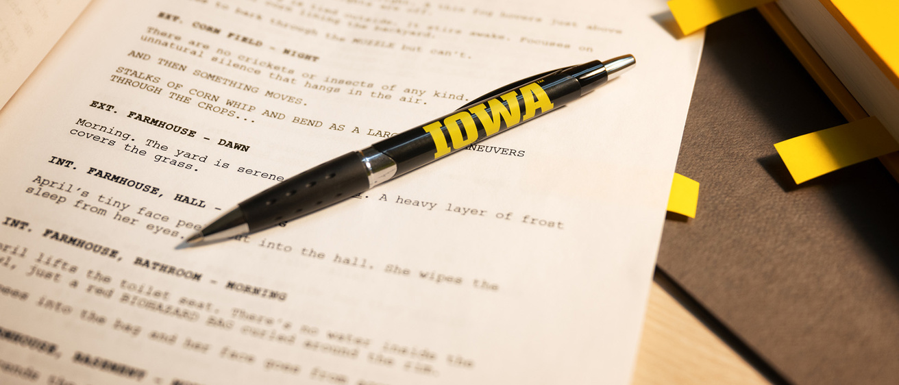 a pen with the Iowa logo rests on a screenplay