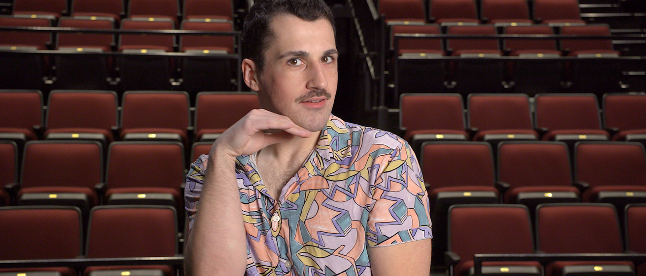 A person sitting in an empty theater with a hand under their jaw