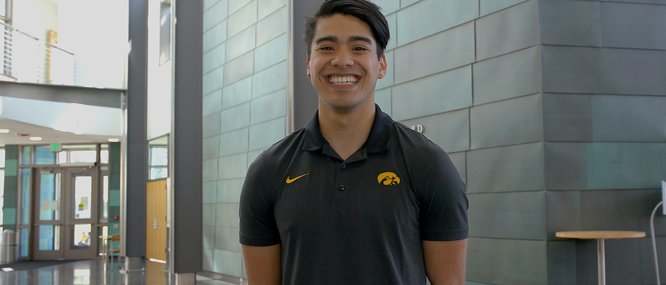 A man standing with his arms behind his back and smiling