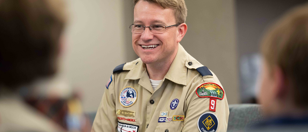 A man smiling talking to a group of kids