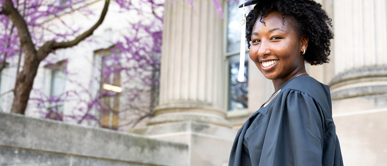 A woman standing on a set of steps in a cap and gown