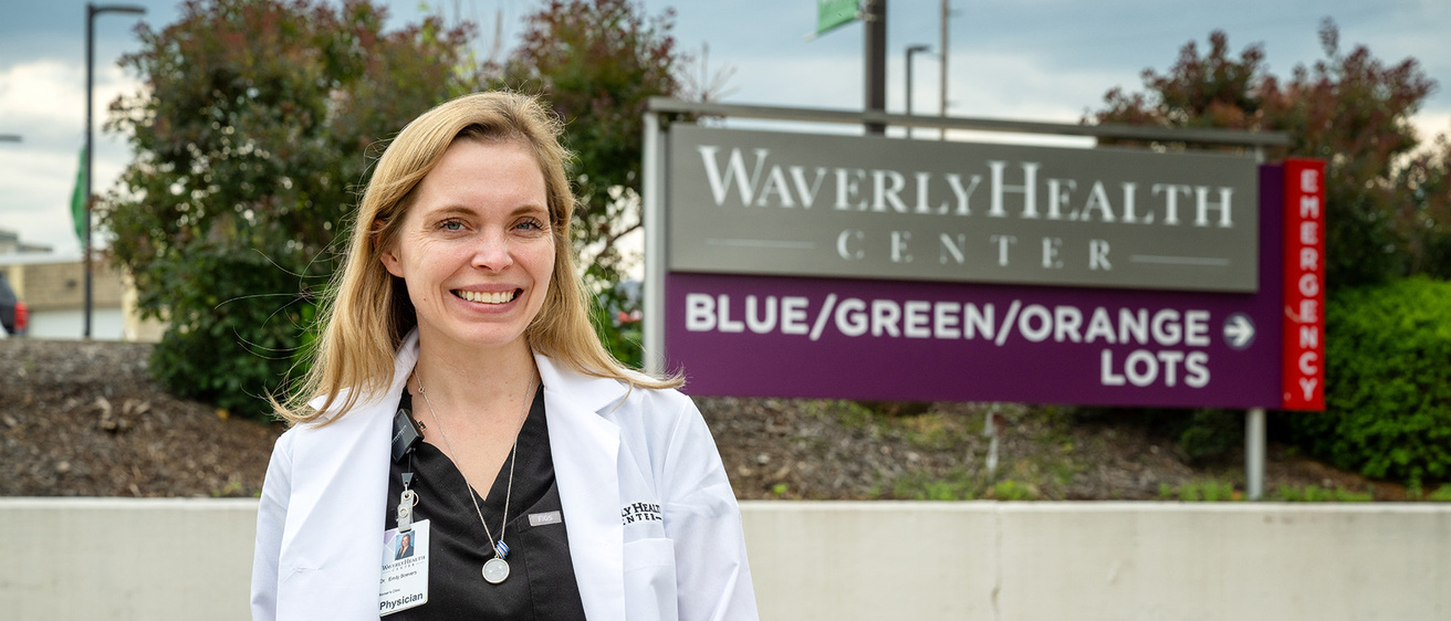 A woman smiling with a healthcare sign in the background