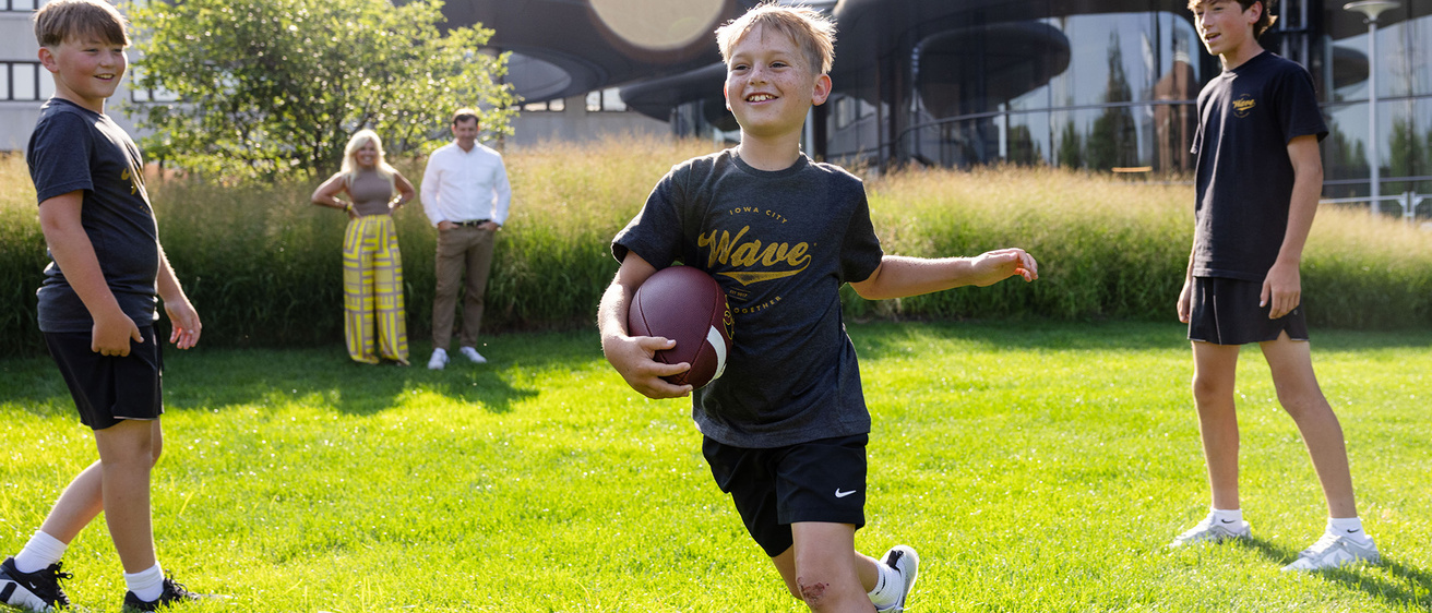 A boy playing football with his family