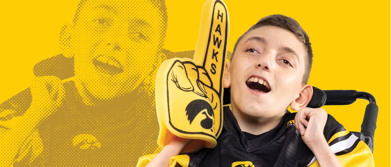 A boy sitting in a wheel chair with a foam finger
