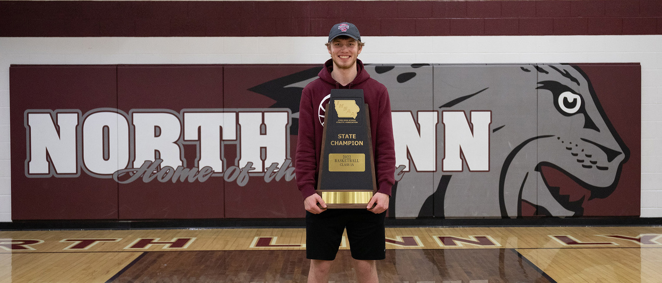 a high school student standing in a gymnasium holding a trophy