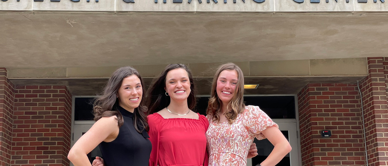 Three women standing together outside a hearing center
