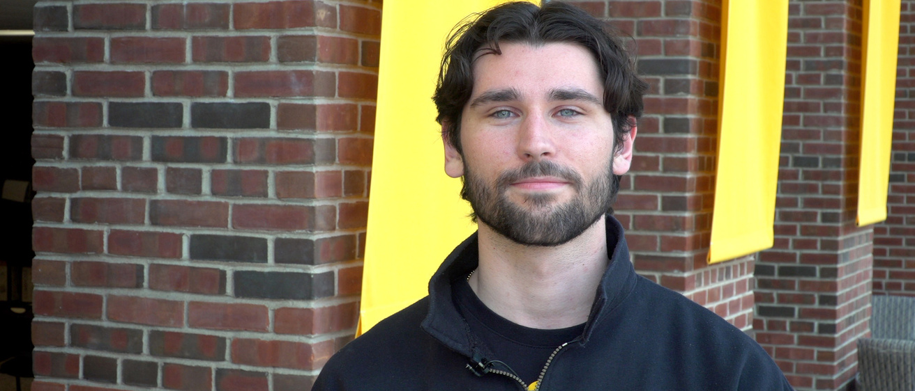 A man standing in front of a brick wall