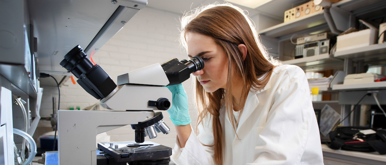 a woman in a lab using a microscope