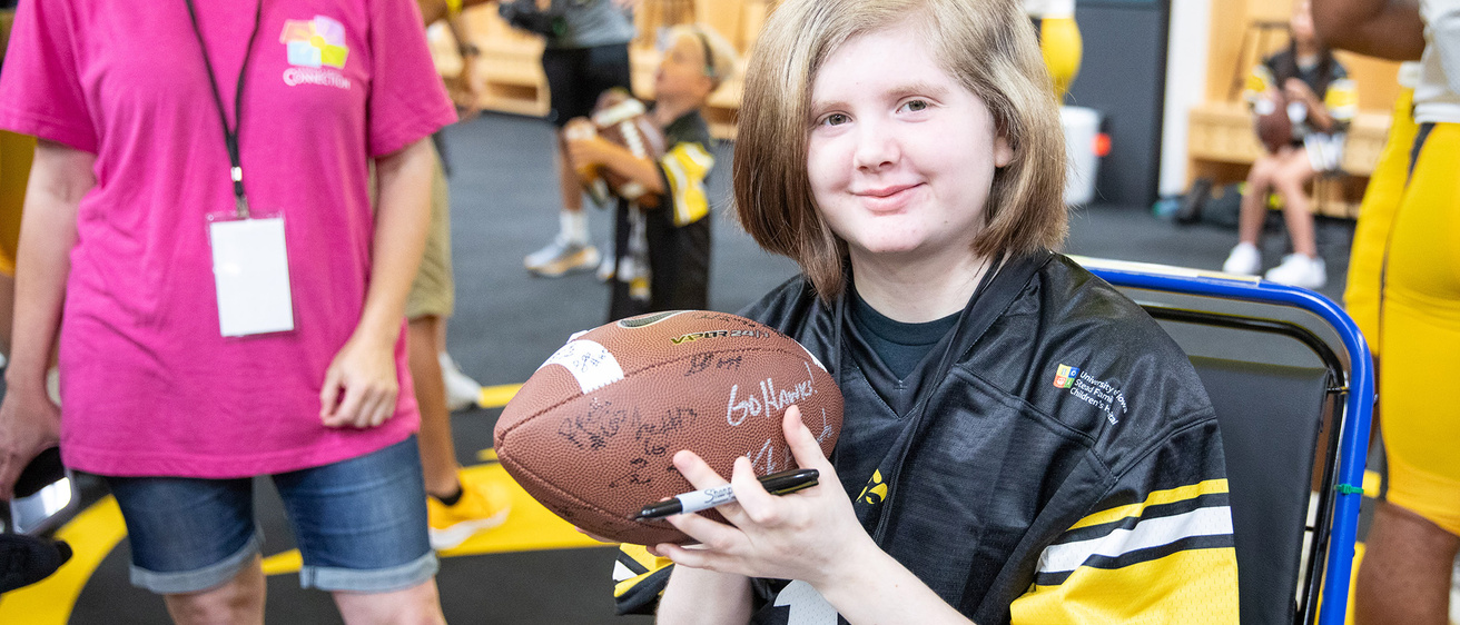 A girl holding a football with different signatures on it