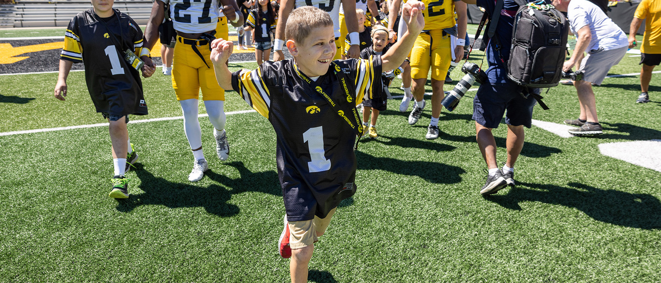 A young boy running out onto a fooball field