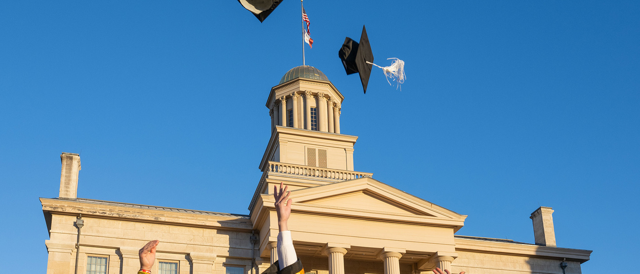 grads standing near old capitol, throwing caps in the air