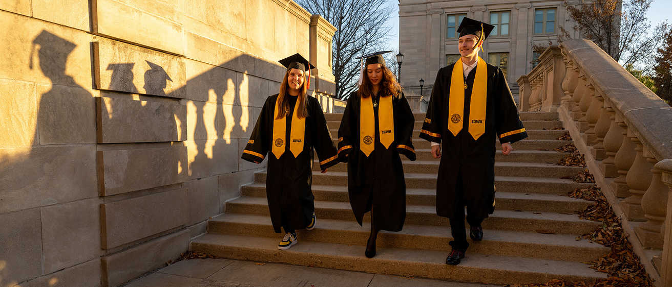 three University of Iowa grads walking down steps on the pentacrest