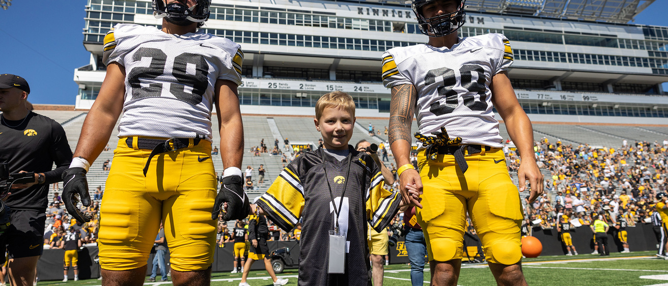 A young boy standing between two football players