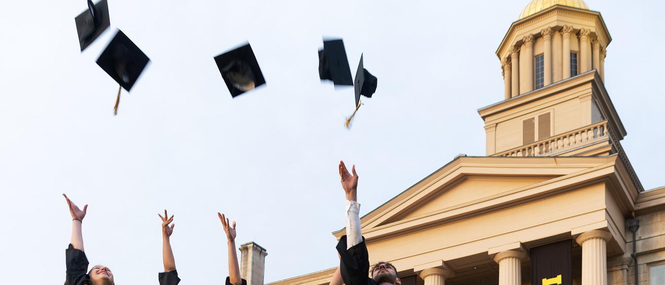 grads standing near old capitol, throwing caps in the air