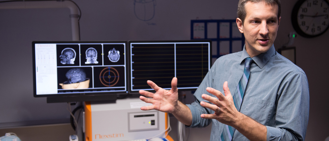 A man explaining some images on a screen behind him