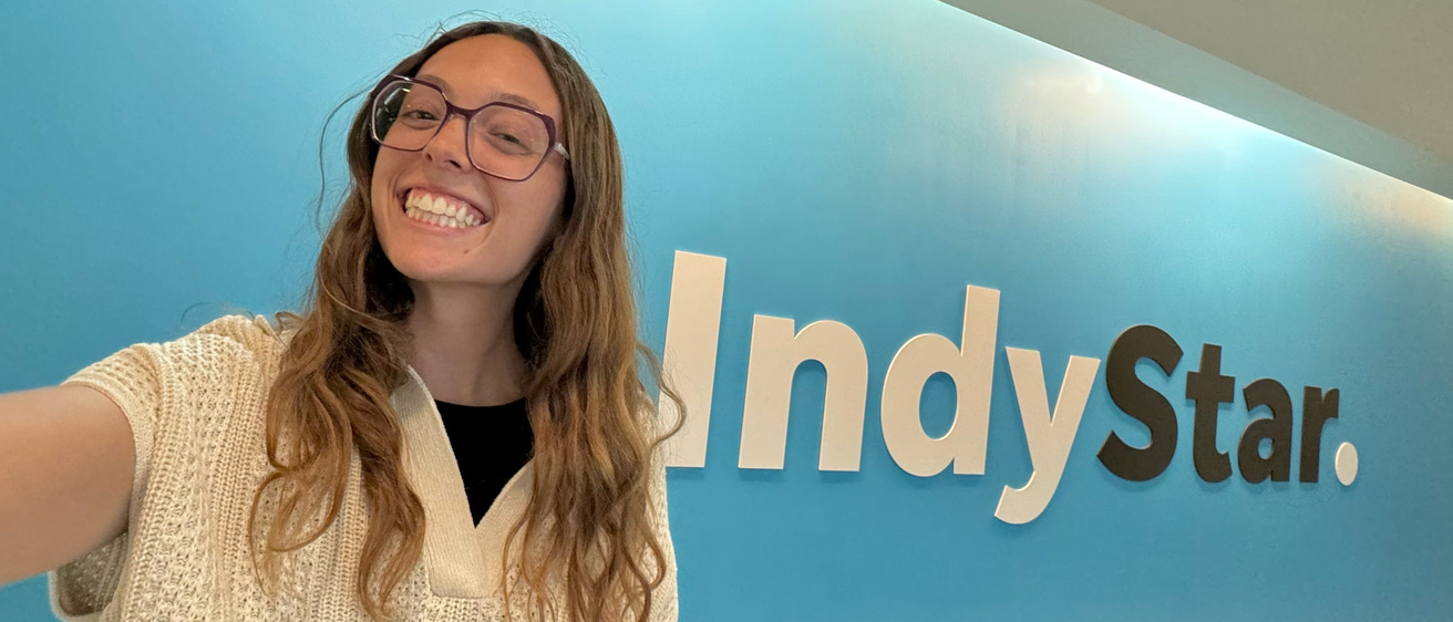 University of Iowa grad Grace Smith taking a selfie in front of the Indy Star logo on a wall
