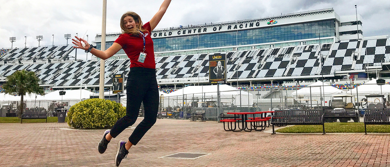 a woman leaping in the air outside of a race track