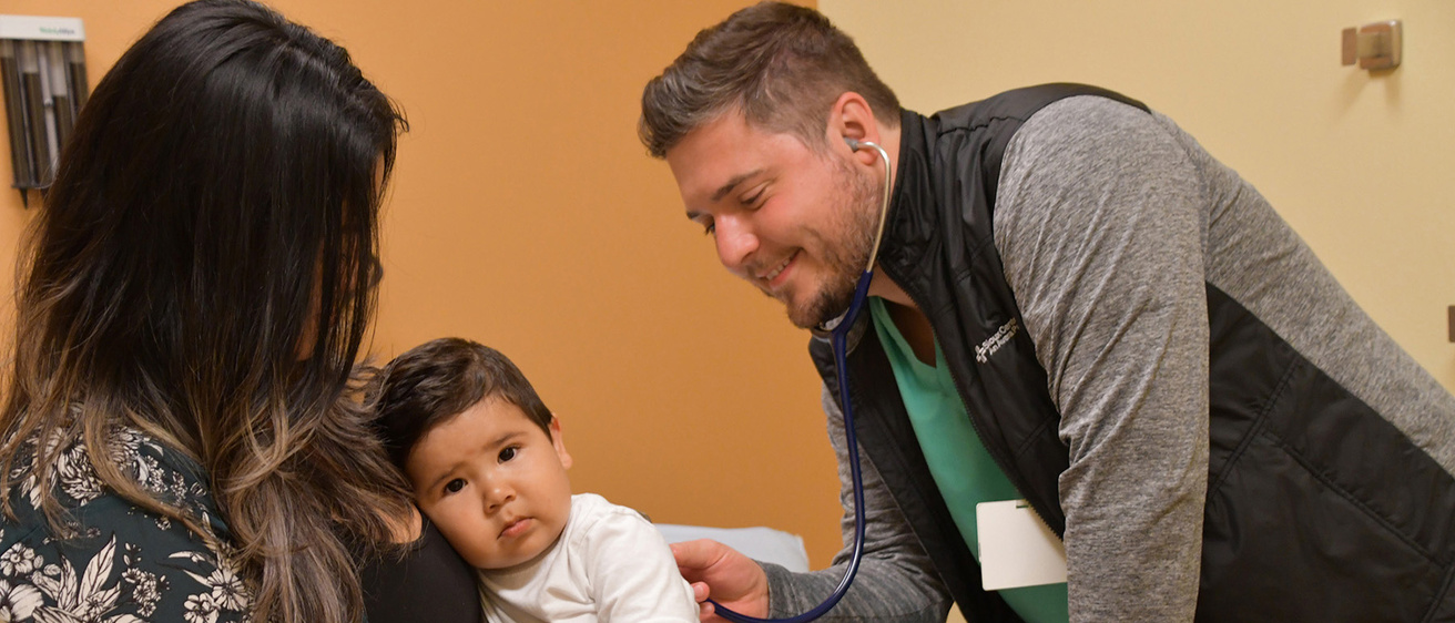 a doctor examines a young boy who is being held by a parent