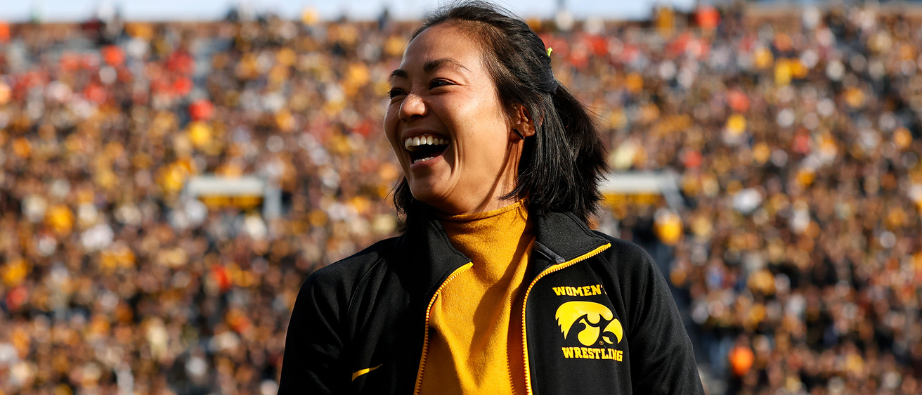 A woman smiling in front of a crowded stadium