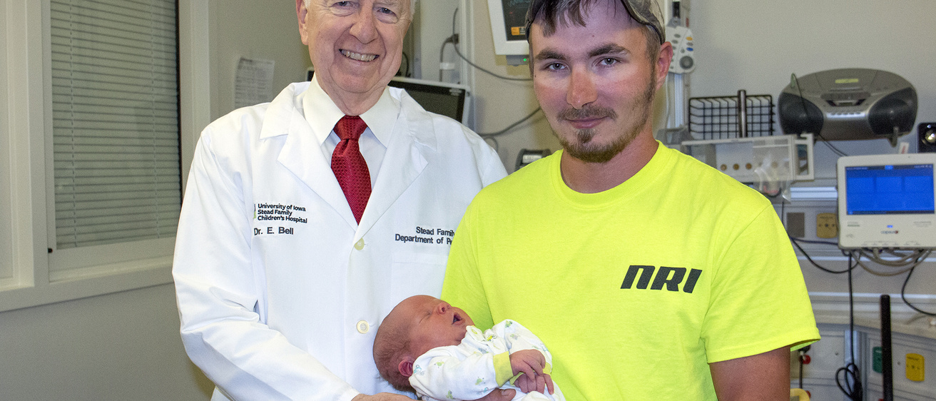 A doctor standing with a man holding his baby