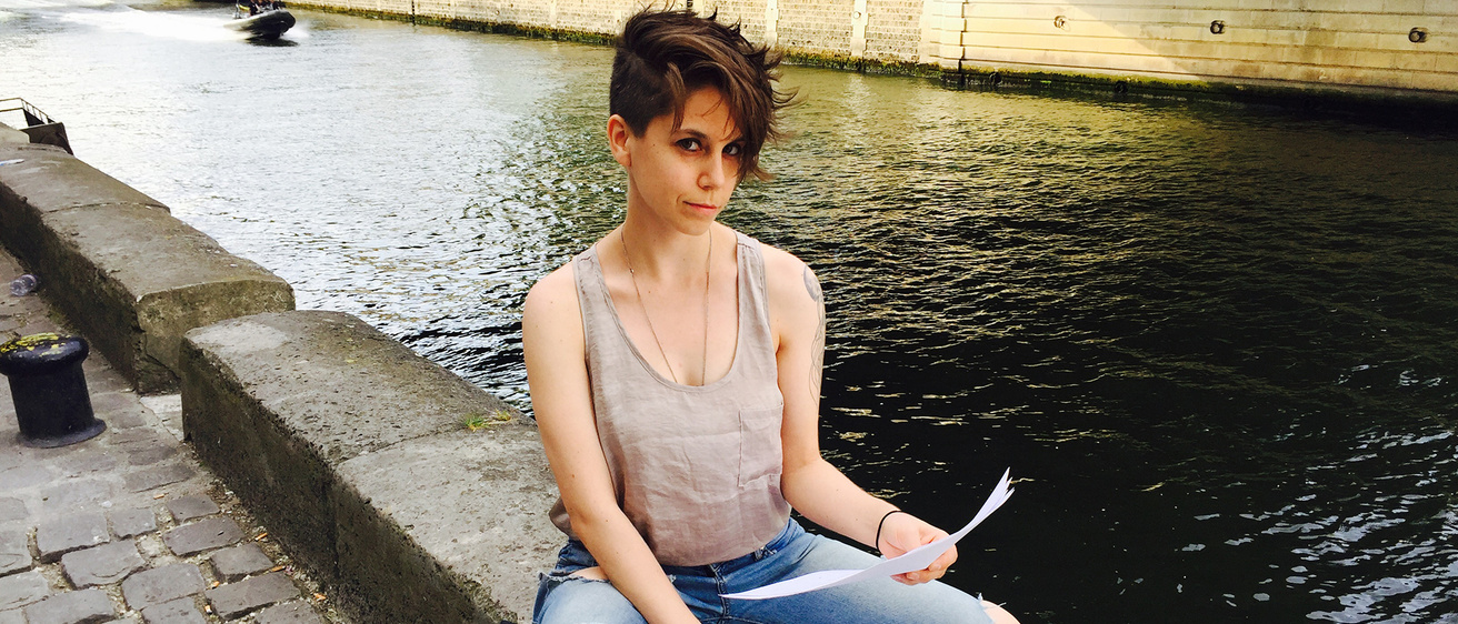 A woman sitting on a ledge near a river