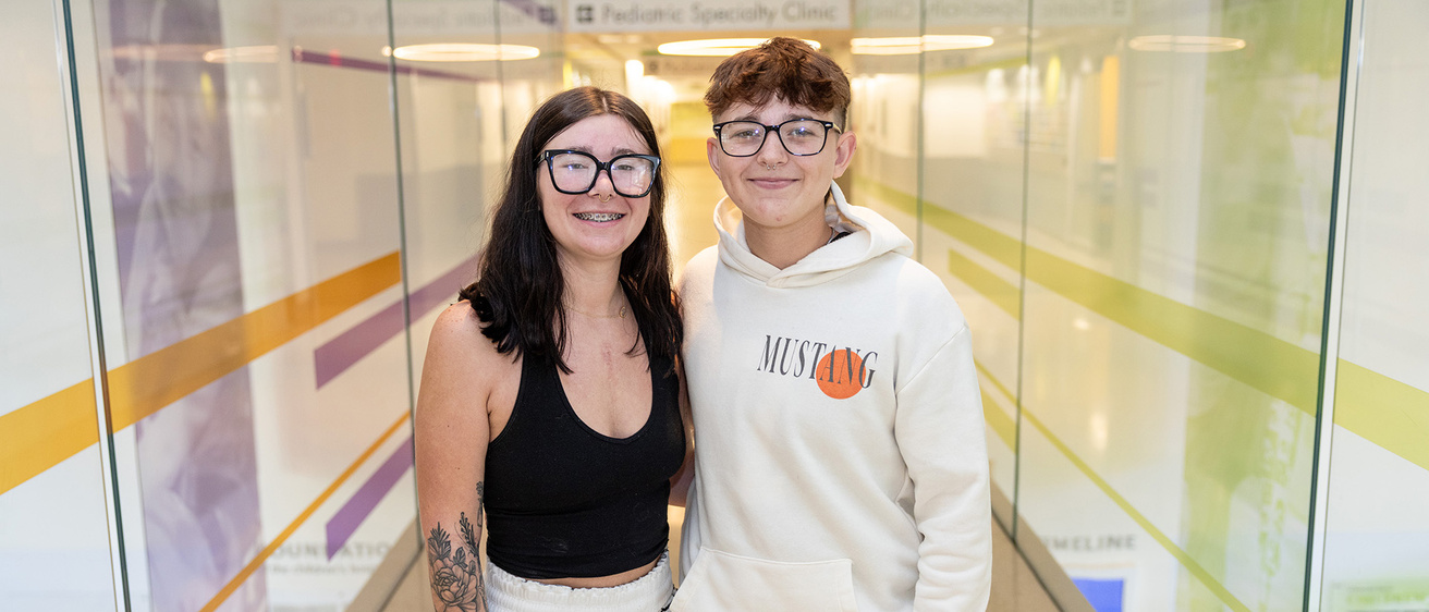 two siblings standing in the hallway of a health care facility