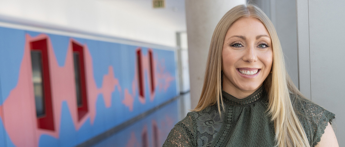 a woman standing in a hallway that has a colorfully painted wall