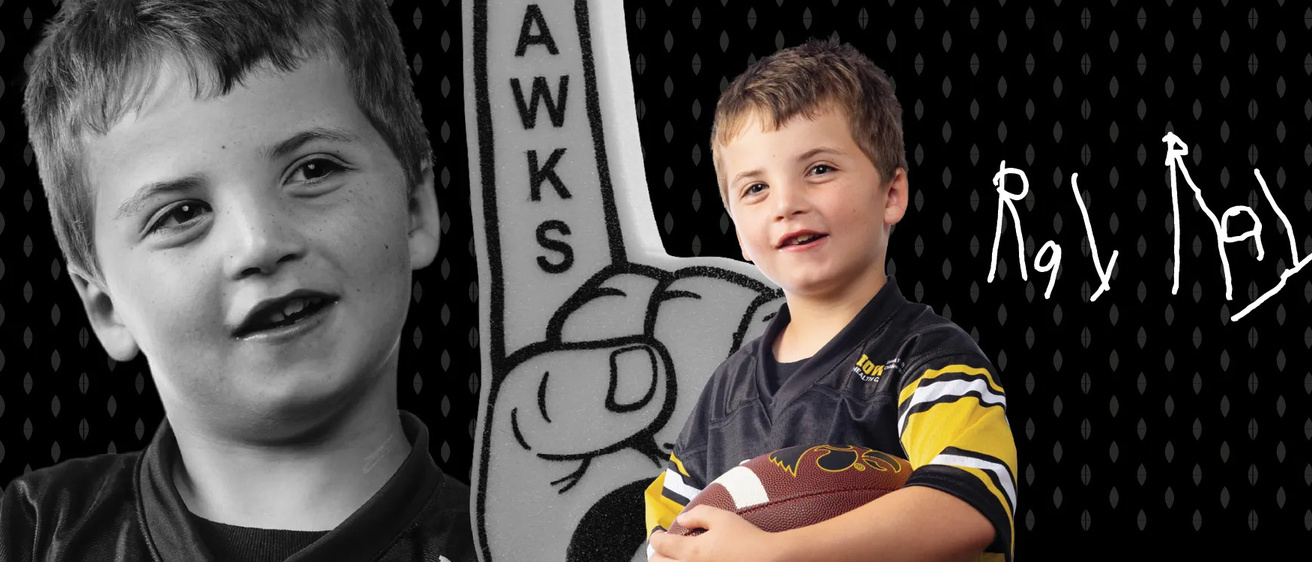 Kid Captain Ray Walker holding a football; the photo backdrop features a foam finger and Ray's signature