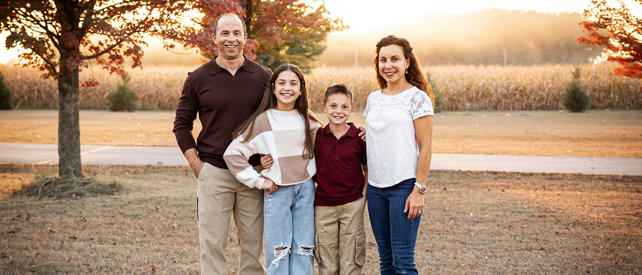 a family of four posing for a portrait in an outdoor setting
