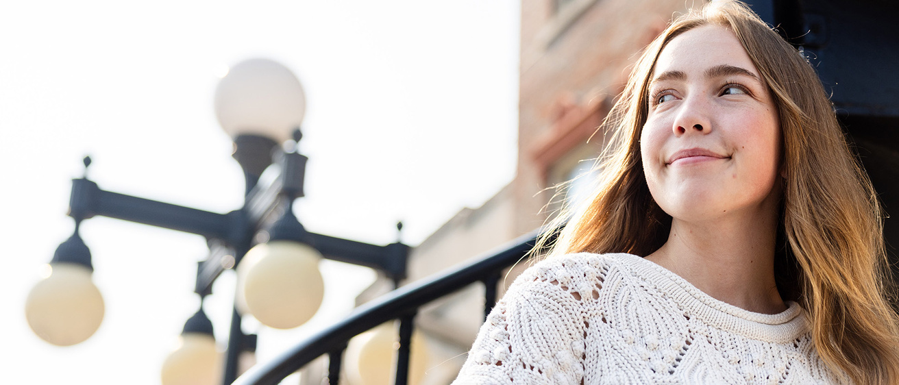 a woman standing near a lamppost, looking to her right
