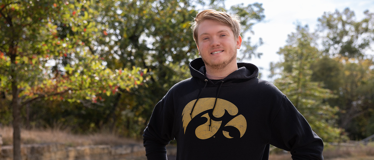 a young man wearing a sweatshirt with the tiger hawk logo stands outdoors