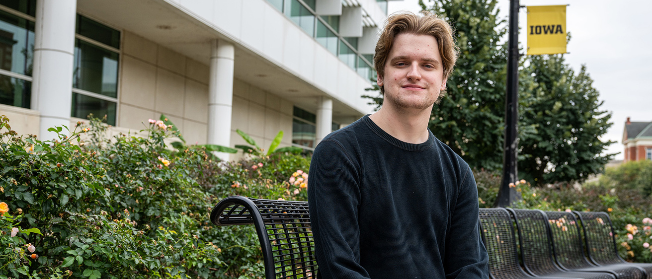 University of Iowa student Tyler Draayer sits on a bench on campus