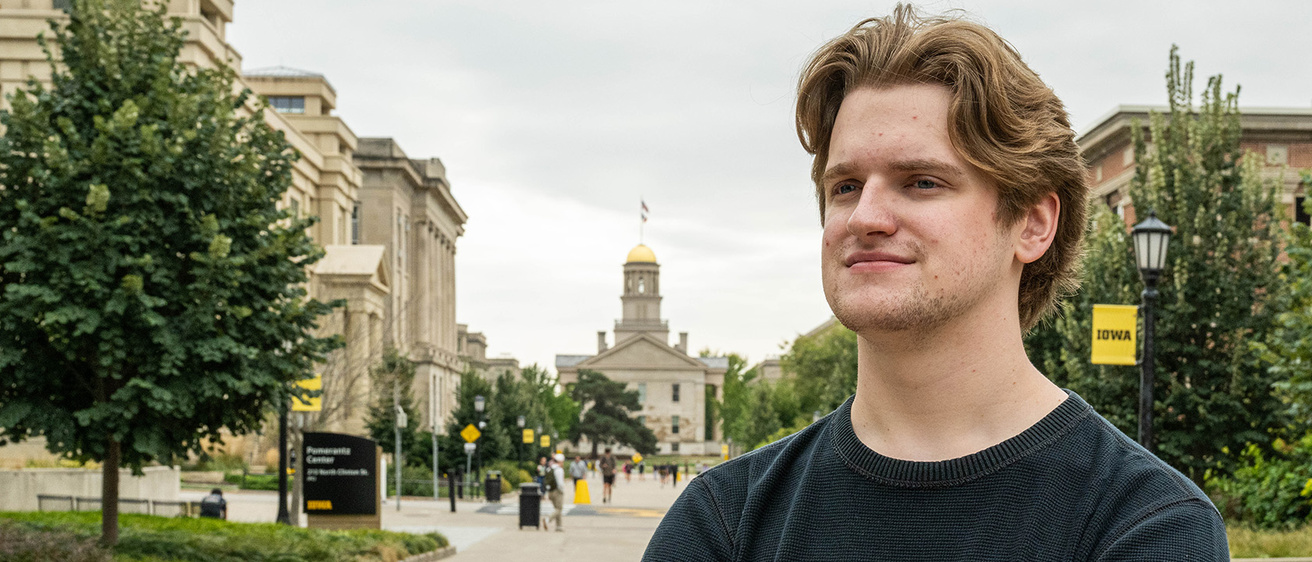 University of Iowa student Tyler Draayer stands on the UI campus; Old Capitol is visible in the background