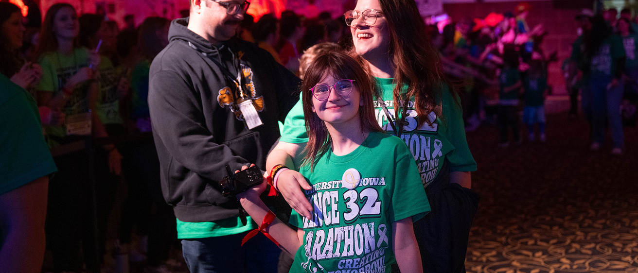 a family at a Dance Marathon Big Event at the University of Iowa; hundreds of dancers are in the background