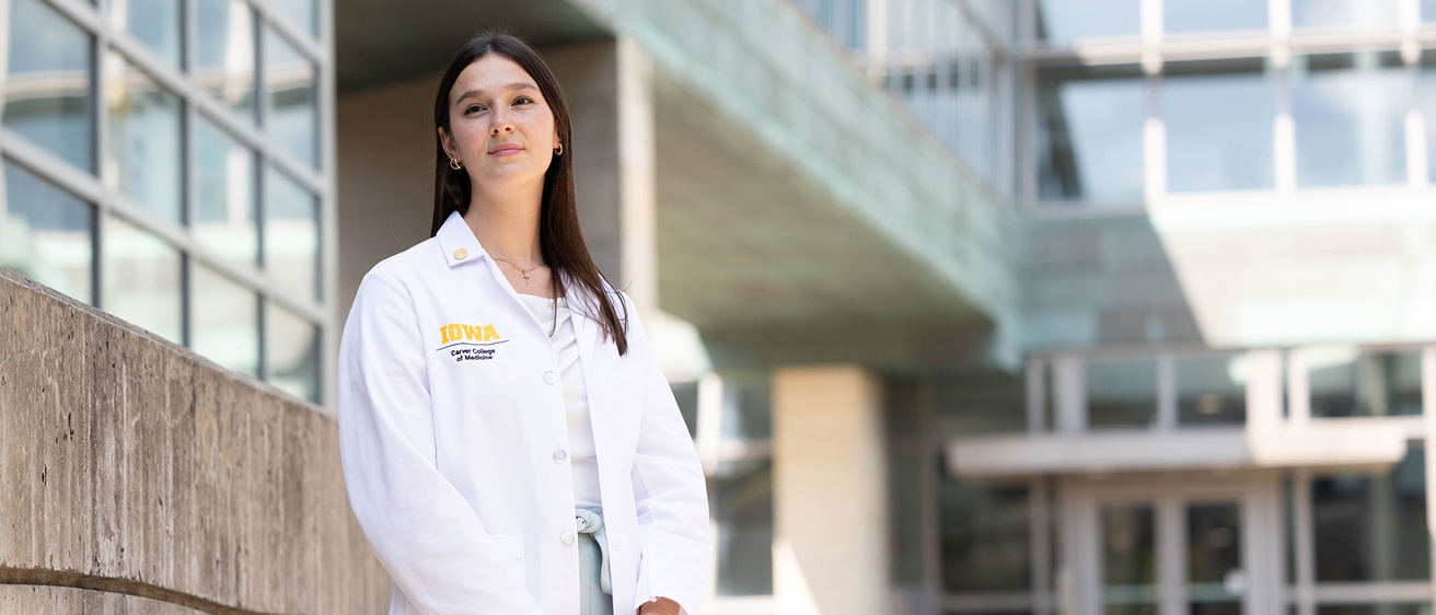 a woman wearing a white coat stands outside a medical building
