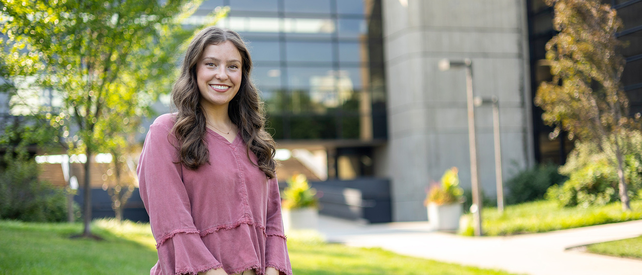 a woman stands outdoors on the university of iowa campus